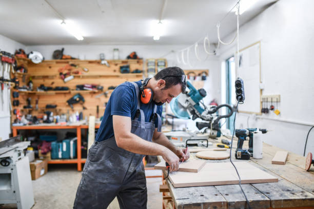 istock Focused Carpenter Measuring Small Plank And Getting Ready To Cut It In Workshop 1411285166