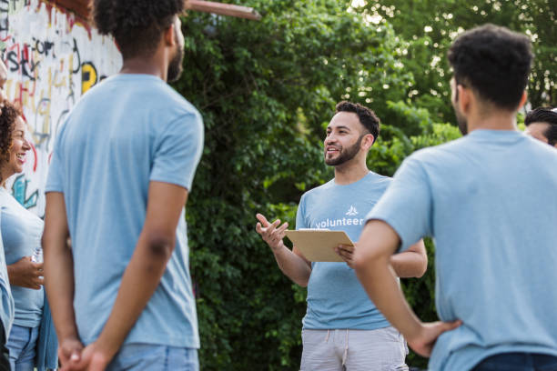 istock Male volunteer stands with group to explain the project 1411288727