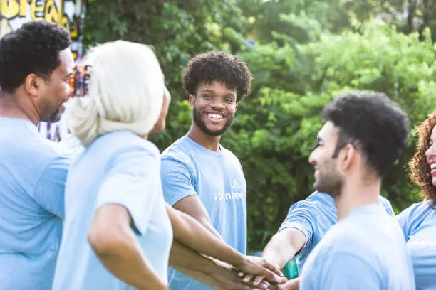 Photo of Diverse group stands near each other and stacks their hands