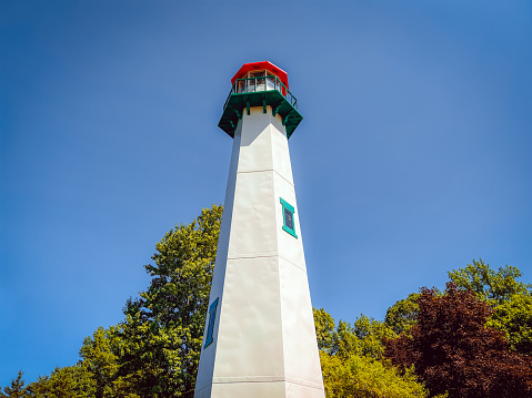 Beautiful Lighthouse Located at the New Buffalo Welcome Center. This is the first rest stop when crossing the Southern border and entering the great state of Pure Michigan. White lighthouse with green and red details set against a clear blue sky and leafy trees.