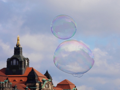 Soap bubbles fly under a white-blue sky