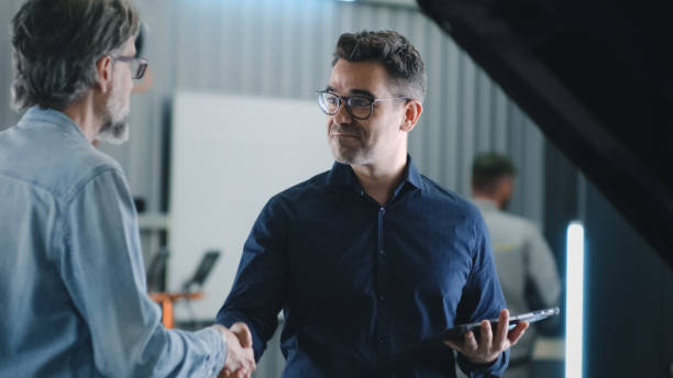 Manager with tablet working in car service Manager in a suit with a tablet shaking hands with a male client after car diagnostics in a car service repair shop auto repair shop mechanic digital tablet customer stock pictures, royalty-free photos & images