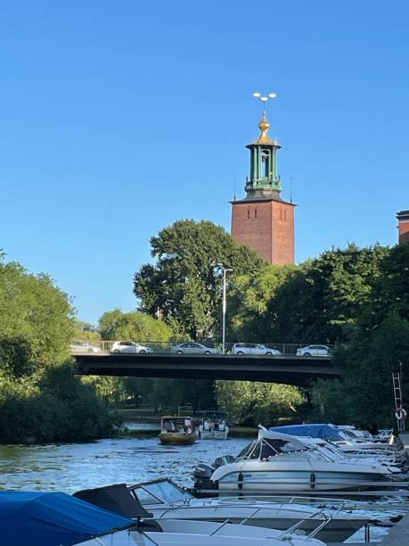 Stockholm City Hall unusual angle Stockholm City Hall with boats, water, and bridge with cars kungsholmen stock pictures, royalty-free photos & images