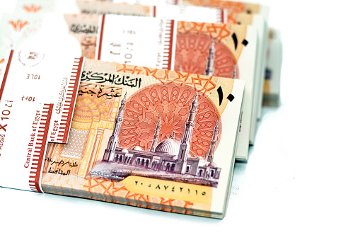 Stacks of the new first Egyptian 10 LE EGP ten pounds plastic polymer banknote features Administrative capital's grand mosque Al-Fattah Al-Aleem, the pyramid and Hatshepsut isolated on white