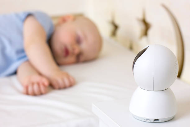 Cute little baby boy sleeping on bed at home with baby monitor camera. Cute little baby boy sleeping on bed at home with baby monitor camera. Selective focus. Child daytime sleeping. Modern technology. indoor wireless antenna stock pictures, royalty-free photos & images