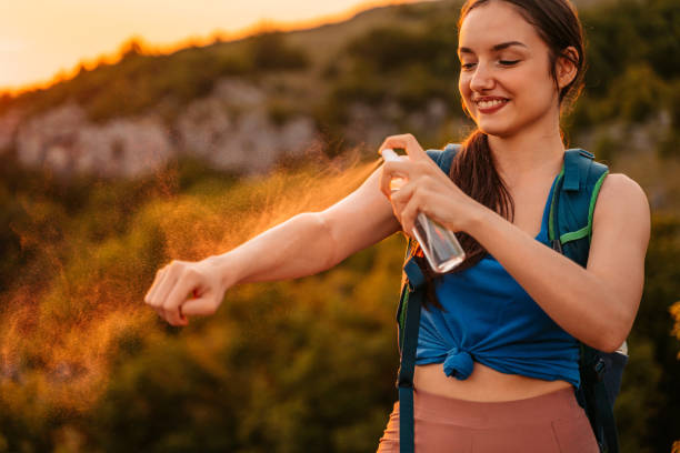 mujer joven aplicando repelente de mosquitos en la cima de la montaña - insect repellant mosquito bug bite spraying fotografías e imágenes de stock