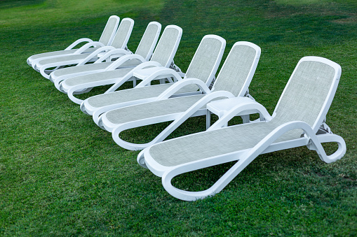 Side by side rows of white sun loungers.