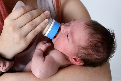 New mother feeding her infant daughter formula.
