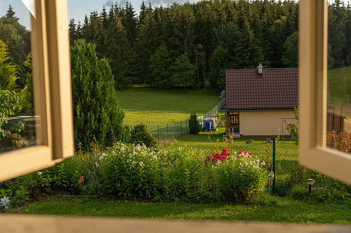 view through an old weathered vintage window to a picturesque green garden somewhere in the mountains, countryside, vivid colors, Slovakia, Europe