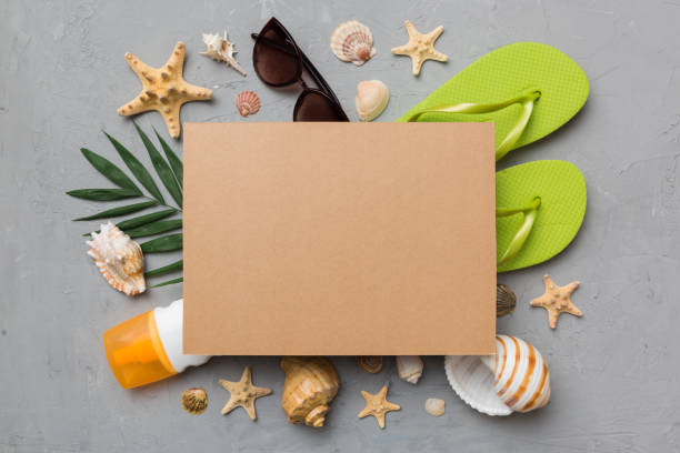 istock Summer time concept with blank greeting card and blank craft paper on colored background. Seashells from ocean shore in the shape of frame separated with space for text top view 1411301867