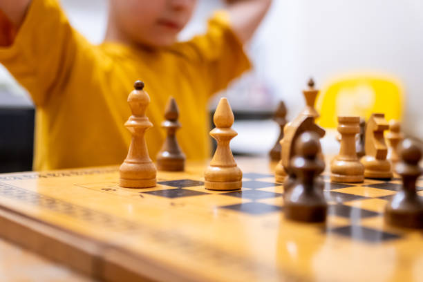 istock Brunette boy playing a game of chess on large chess board at home. selective focus. 1411302769