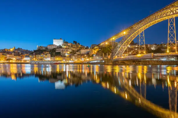 Reflections of the Dom Luís I Bridge in Porto, Portugal at night.