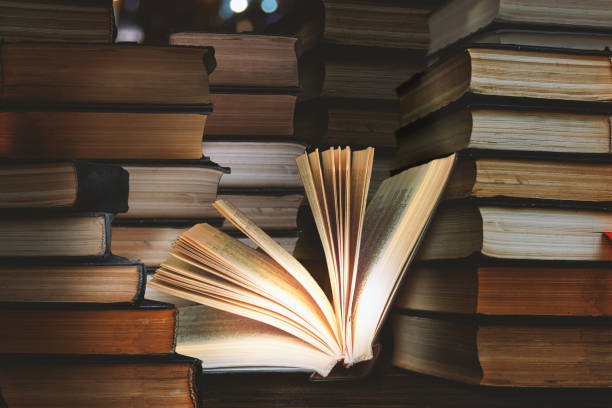 istock rare book stack in dark room. Open book, hardback books on wooden table. Education background. Back to school 1411308632