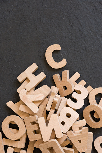 Many wooden letters on black background. Copy space.
