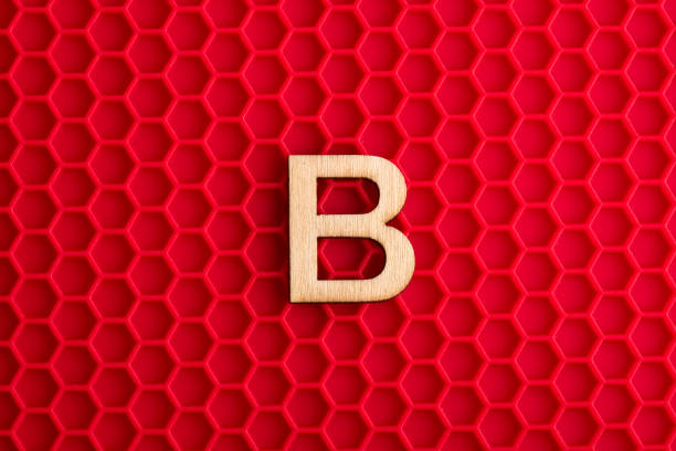 istock Alphabet letter B - White piece on silicone background with red hexagons 1411315742