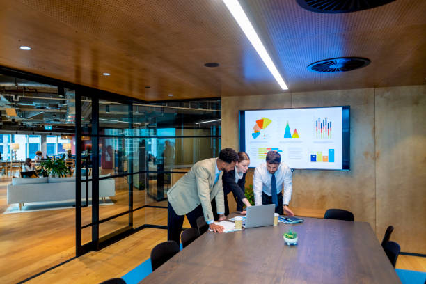 деловые люди, работающие на ноутбуке в современном офисном зале заседаний. - data analyzing marketing strategy стоковые фото и изображения