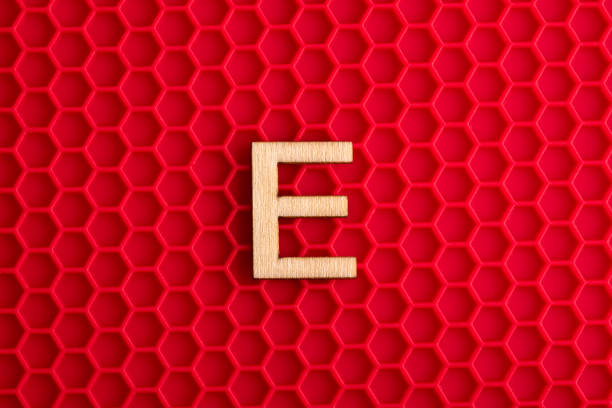 istock Capital letter E - White piece on silicone background with red hexagons 1411316295
