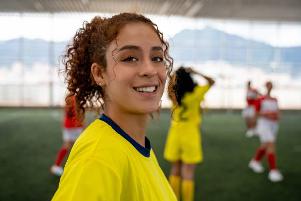 Happy female soccer player smiling at the field while playing a game