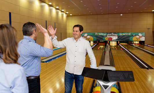 Happy group of friends bowling and celebrating a strike â sports and recreation