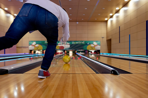 Man bowling and throwing the ball in the alley - sports and recreation concepts