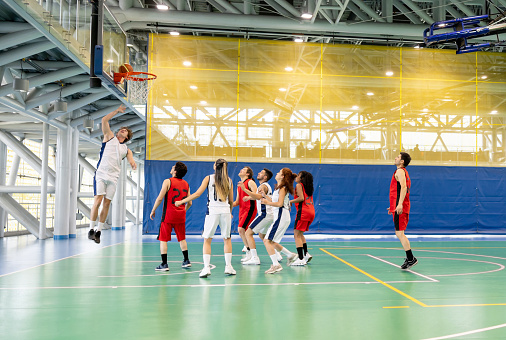 Group of male and female players playing basketball at the court - co-ed sports concepts