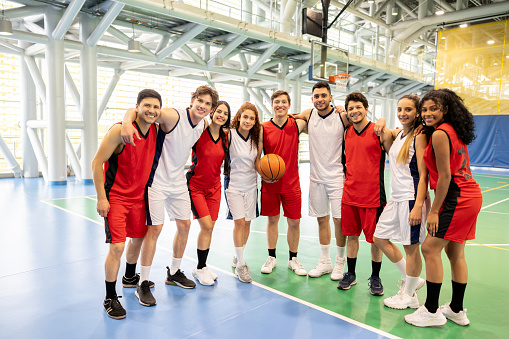 Co-ed group of Latin American basketball players smiling at the court and looking at the camera