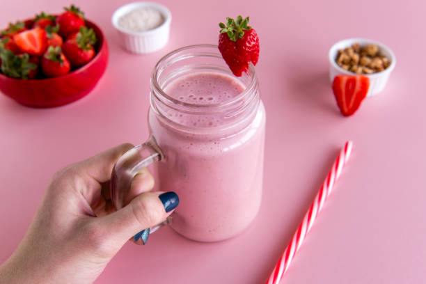 hand holding a strawberry smoothie cup, healthy shake of strawberry with milk.