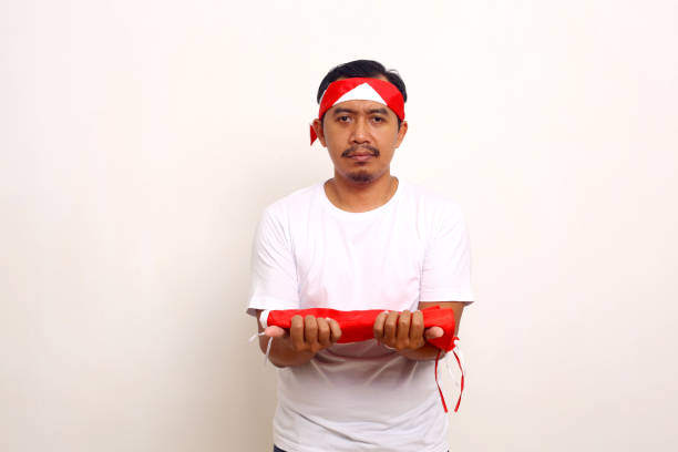 istock Calm asian man standing while holding indonesian flag. Independence day concept. Isolated on white 1411323861