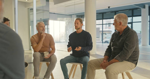 istock Men talking and sharing their struggles with addiction during a AA meeting while sitting on chairs during group therapy. Male patients getting advice and support during counseling at rehab facility 1411325441