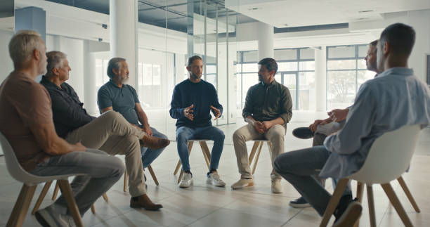 istock Diverse support group during a meeting with a professional therapist. Group of employees looking serious during a team counseling session. Mental health and wellness in the professional workplace 1411325484