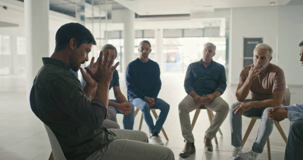 istock Men in a group therapy session with with a therapist. Grieving widowers getting advice from a grief counsellor, speaking in a trust circle with friends. AA meeting for men only discussing struggles 1411325511