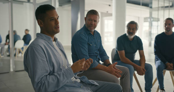 istock Men in an AA support group meeting for alcohol abuse, talking while sitting in a circle during a therapy session. Male colleagues discussing feelings and emotions in a team psychology meeting 1411325515