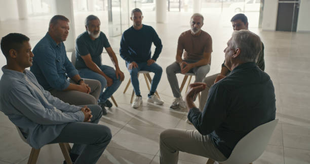 istock A team of men sitting in a circle during a therapy session. Diverse colleagues talking about their emotions in a support group with a professional psychologist in a office or mental health workshop 1411325520