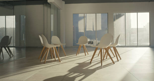 istock Empty chair in a room prepared for group therapy session. Open seats forming a circle to interact during physiotherapy in a community center or rehab facility. Space for team building or AA meeting 1411325534