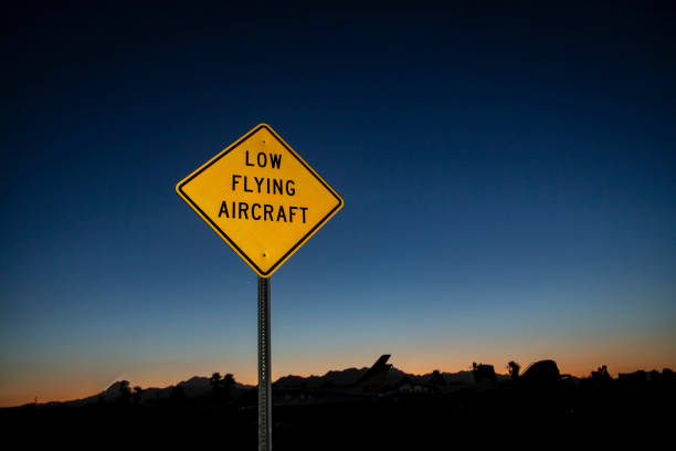 image horizontale d’un panneau jaune avertissant d’un aéronef volant à basse altitude pris au lever ou au coucher du soleil - airplane stunt yellow flying photos et images de collection