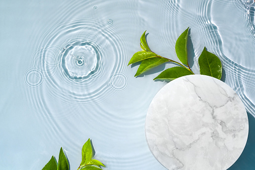 Minimal modern empty product display on water background with waves and splashes and green plants. Concept showcase for a new product, advertising sale, banner, presentation, natural moisturizing collagen cosmetics