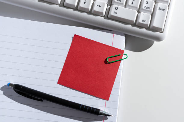 istock Sticky Note With Important Message Clipped On Opened Notebook On Desk With Pen And Keyboard. Crutial Information Presented On Memo Attached On Notepad Next To Pencil. 1411337343