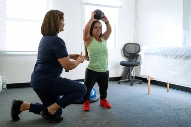 Physiotherapist performing techniques with a female client with dwarfism