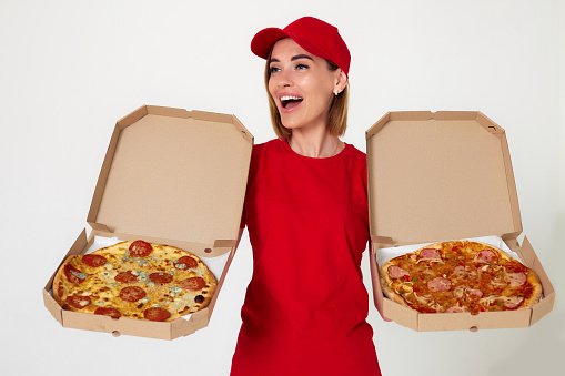 pizza delivery girl in uniform showing pizza inside boxes on white background