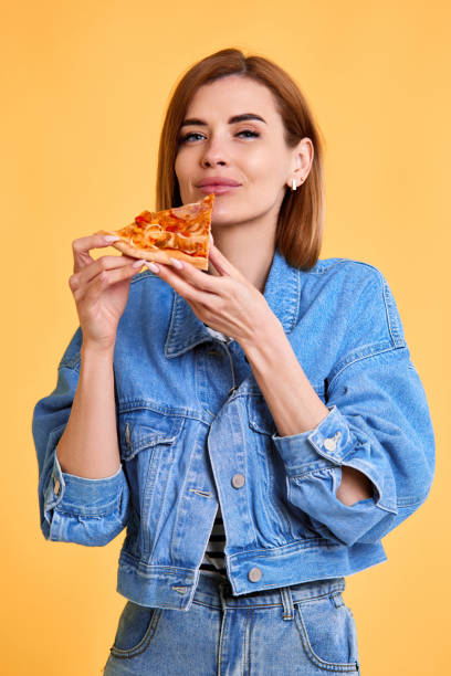 istock young woman with pizza slice on yellow background. 1411338802