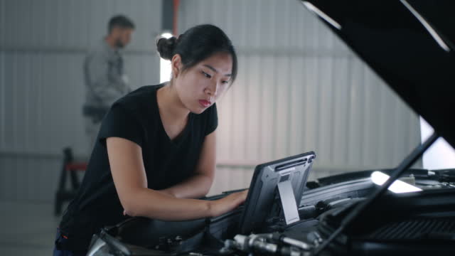 Female mechanic checking car with tablet