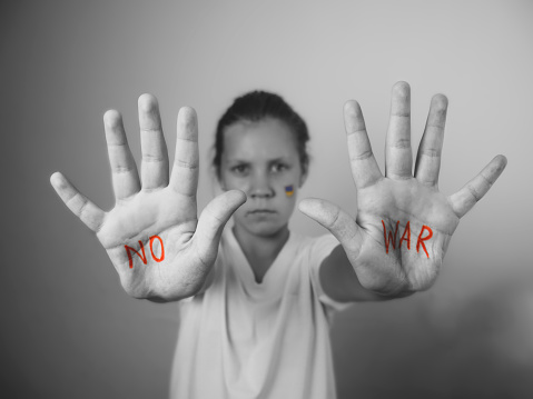 stop the war, the hands of a child,  child with the message of peace without war is written on the hands of a child there is no war, the Ukrainian flag on the girl's cheek,black and white photo, monochrome