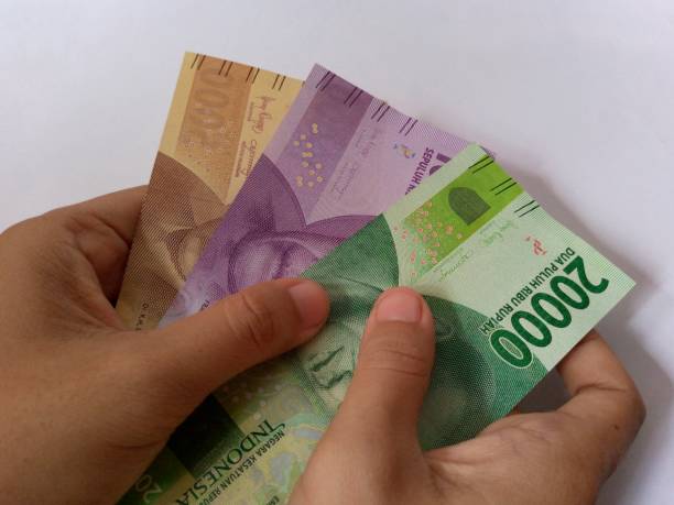 istock Hand holding twenty thousand, ten thousand and five thousand rupiah bills on a white background 1411344970