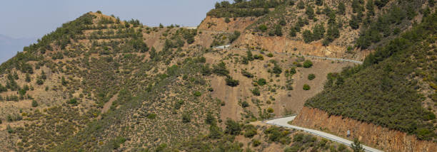 istock Road climbing as it winds around natural undulations or arid mountainside 1411347745