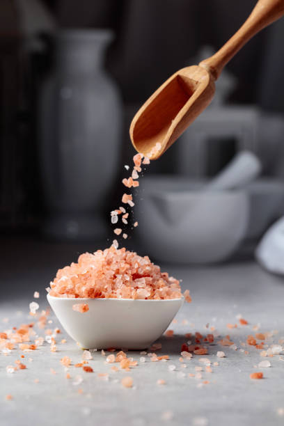 istock Pink salt in crystals is poured into a small white bowl. 1411347922