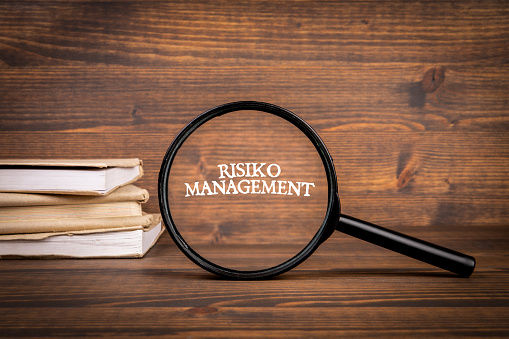 German word Risiko Management, risk management. Magnifying glass with text.