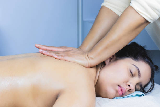 jeune femme latine brune détendue recevant un massage à l’huile décontractant dans un salon de spa - massaging spa treatment stone massage therapist photos et images de collection