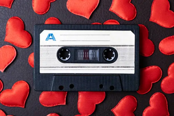 Old Audio Tape Cassette on a Scattered Red Hearts closeup