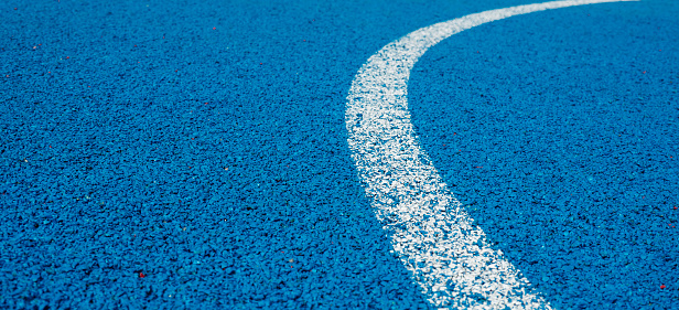 Colorful sports court background. Light blue field rubber ground with curved white line outdoors. Top view.