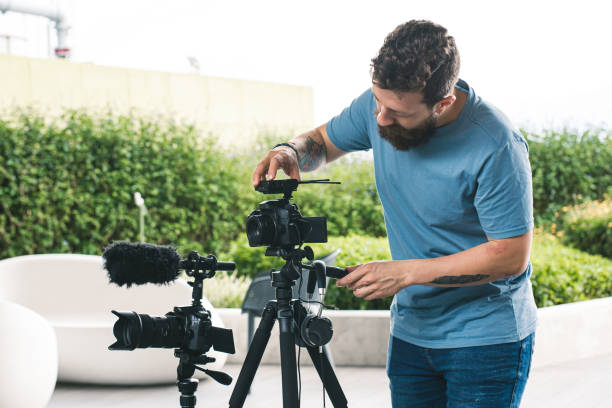 istock person using a camera Young man making videos with two digital cameras. Independent worker making a video clip with his photography and video equipment 1411354542